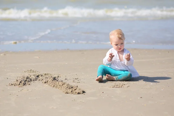 Meisje zitten op het strand — Stockfoto