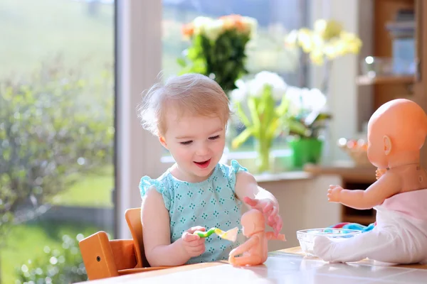 Girl feeding with yogurt her dolls — Stock Photo, Image