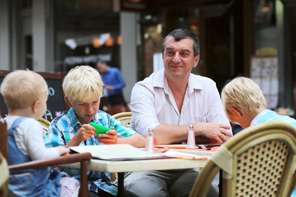 Ojciec z trójką dzieci bawią się w kawiarni — Zdjęcie stockowe