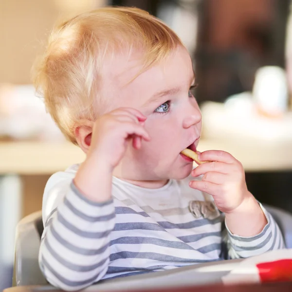 Baby girl eating tasty french fries — Stock Photo, Image