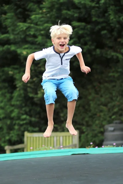 Niño saltando alto en el cielo en el trampolín — Foto de Stock