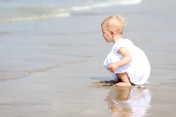 Dziewczynka siedzi na plaży — Zdjęcie stockowe