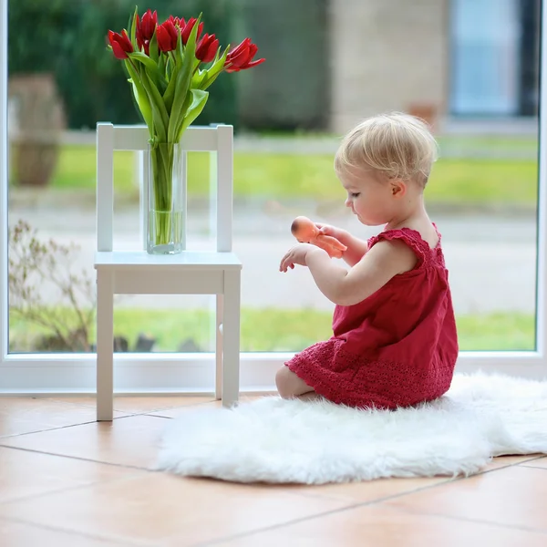 Chica jugando en el suelo con flores de tulipán — Foto de Stock