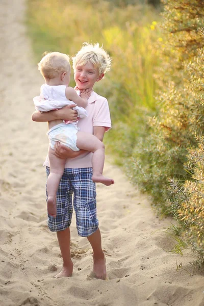 Brother with his baby sister playing together in the dunes — Stock Photo, Image