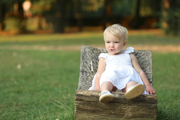 Bebê menina relaxante em uma cadeira de coto — Fotografia de Stock