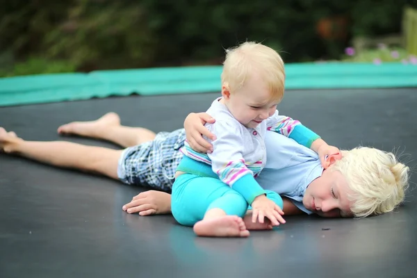 Menino descansando no trampolim com sua irmã — Fotografia de Stock
