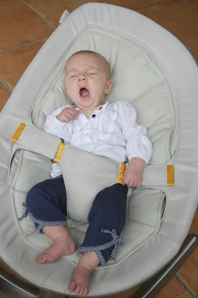 Baby girl yawning in bouncer chair — Stock Photo, Image