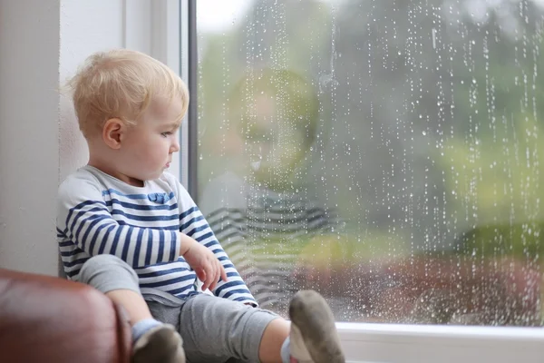 Baby girl looking outside through the window — Stock Photo, Image