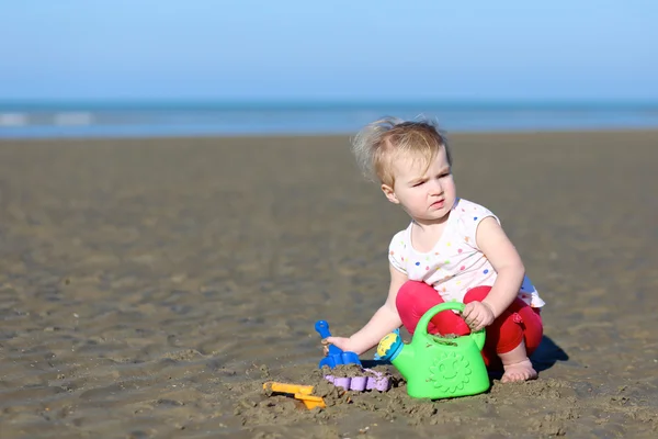 Girl plays with watering can on beach — Stock Photo, Image