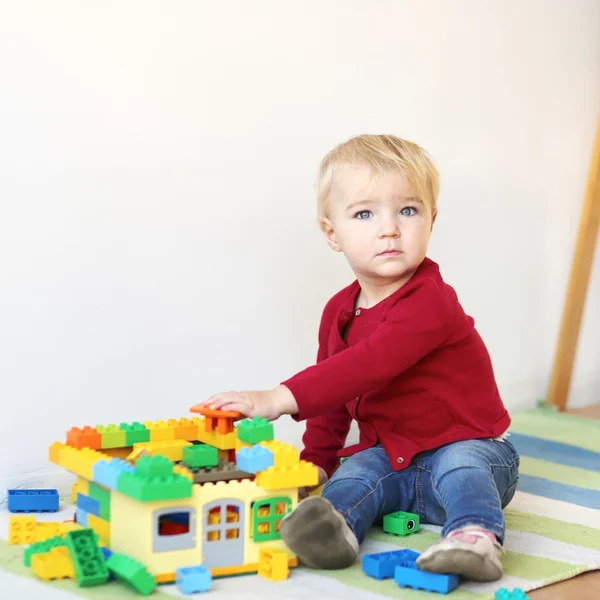 Menina do bebê construindo uma casa com tijolos coloridos — Fotografia de Stock