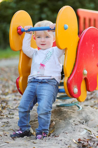 Chica divirtiéndose en el parque infantil montar en el caballo de primavera — Foto de Stock