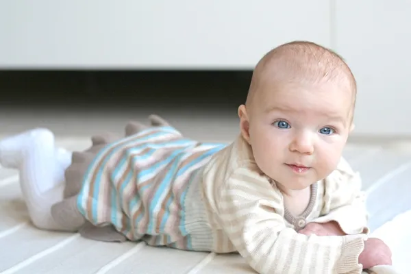 Meisje van de baby op haar buik op een beige deken te leggen — Stockfoto