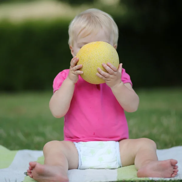 Mädchen beißt auf eine Hälfte Melone — Stockfoto