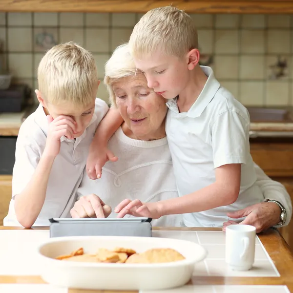 Brüder bringen Großmutter das Spielen am Tablet-PC bei — Stockfoto