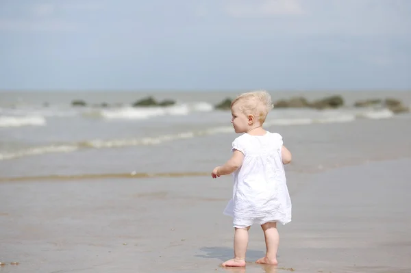 Babymeisje op het strand kijken naar de zee — Stockfoto