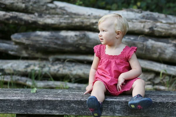 Κοριτσάκι που κάθεται σ ' ένα ξύλινο παγκάκι — Φωτογραφία Αρχείου