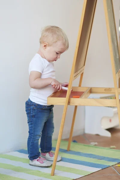 Bébé fille avec craie et crayon à côté du tableau blanc — Photo