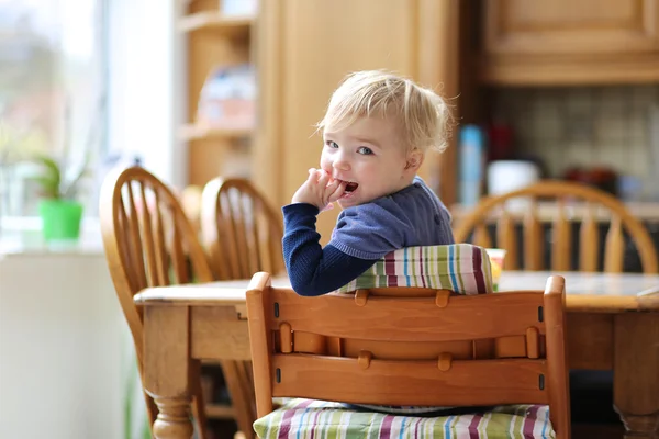 Flicka sitter i köket i barnstol — Stockfoto