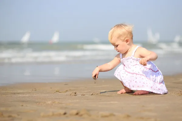 Baby girl drawing picture on a sand — Stock Photo, Image