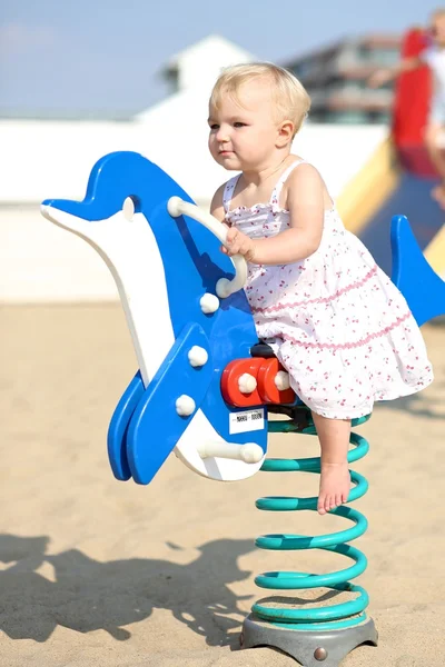 Baby girl rocking on a spring blue dolphin — Stock Photo, Image