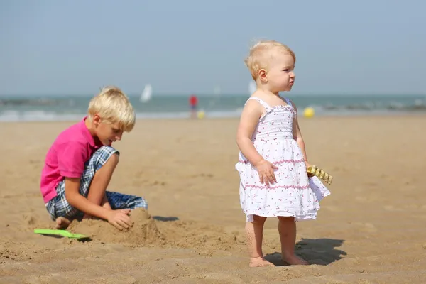 少年と彼の妹を一緒にビーチで遊んで — ストック写真