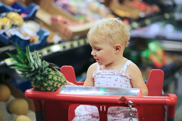 Bebé niña sentada en rojo carrito de compras — Foto de Stock