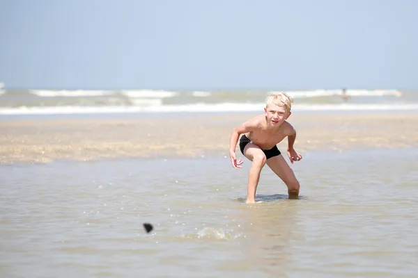 Menino brinca com as pedras na praia — Fotografia de Stock