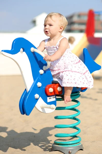 Menina bebê jogando balançando em um golfinho azul primavera — Fotografia de Stock