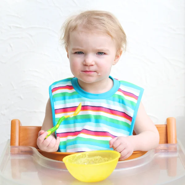 Girl eating porridge with spoon — Stock Photo, Image