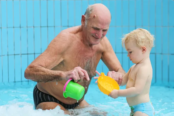Дедушка с внуком играет в бассейне — стоковое фото