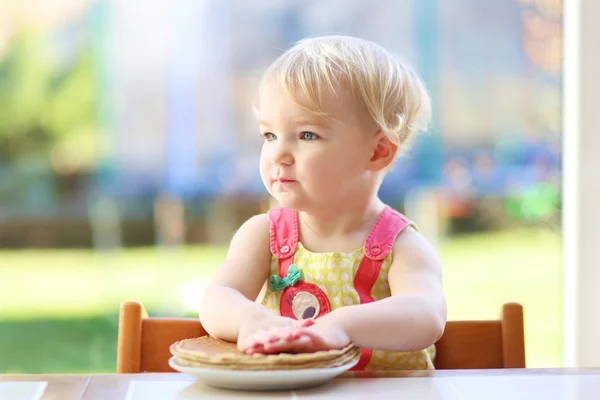 Chica comiendo deliciosos panqueques sentado en la cocina —  Fotos de Stock