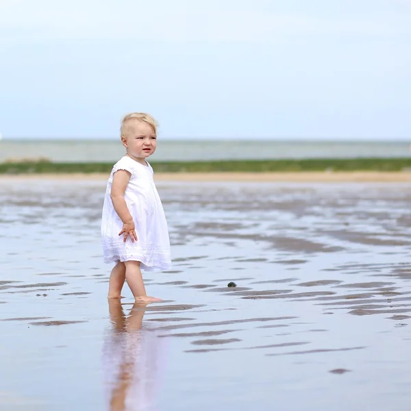 Baby flicka stående på våt sand — Stockfoto