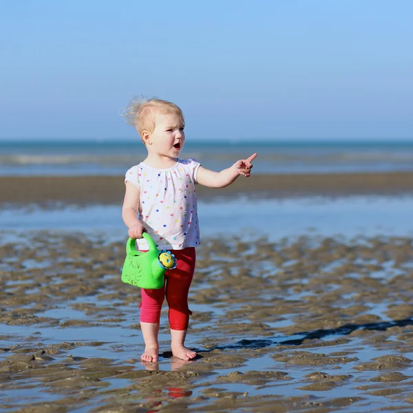 Flicka spelar med vattenkanna på stranden — Stockfoto