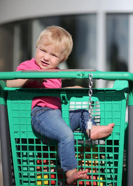 Bambino seduto in un carrello della spesa in un ipermercato — Foto Stock