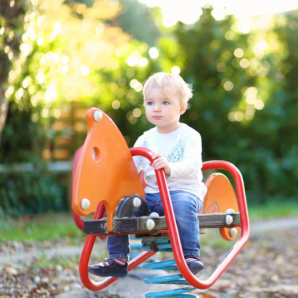 Bebê menina montando no cavalo de primavera — Fotografia de Stock