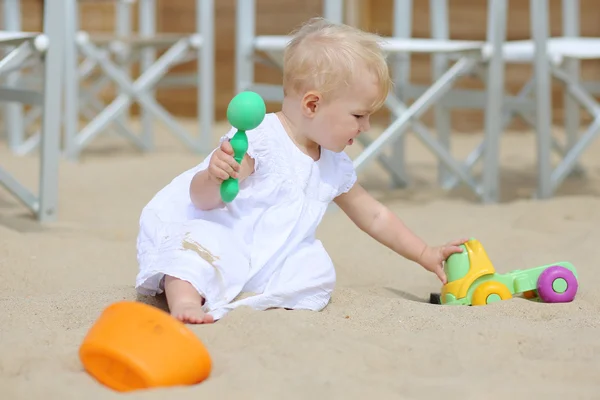 Baby flicka sitter i en sand på lekplats på stranden — Stockfoto