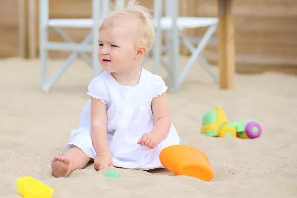 Девочка играет с игрушками на песке на пляже — стоковое фото