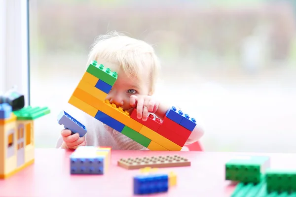 Chica jugando peek-a-boo escondido detrás de bloques de plástico — Foto de Stock