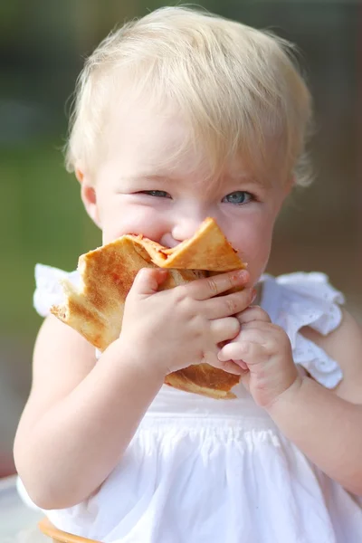 Babymeisje bijten op stuk van smakelijke pizza — Stockfoto