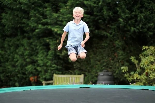 Мальчик прыгает высоко в небо на батуте — стоковое фото