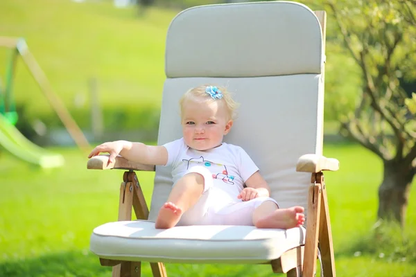 Bebé niña relajándose en una silla de teca de madera — Foto de Stock