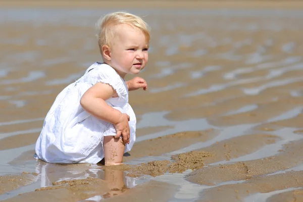 Babymeisje, zittend op een strand — Stockfoto