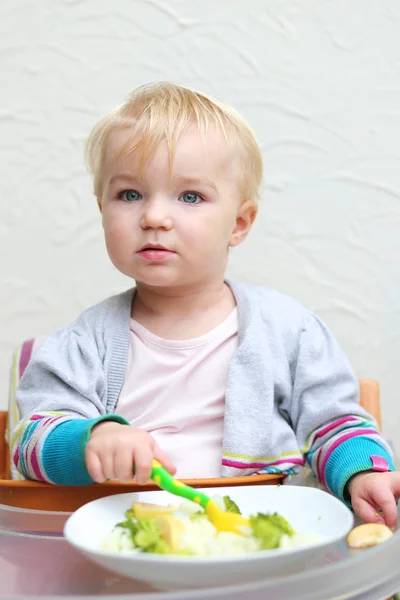 Girl eating boiled vegetables with plastic fork — Stock Photo, Image