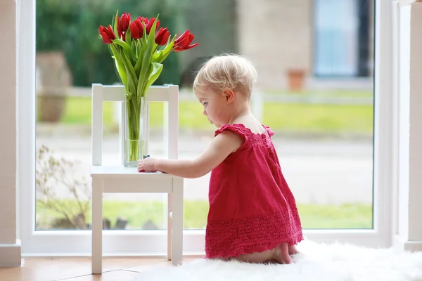 Chica jugando en el suelo con flores de tulipán —  Fotos de Stock