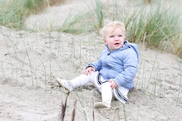 Baby flicka spelar med sand i sanddynerna — Stockfoto