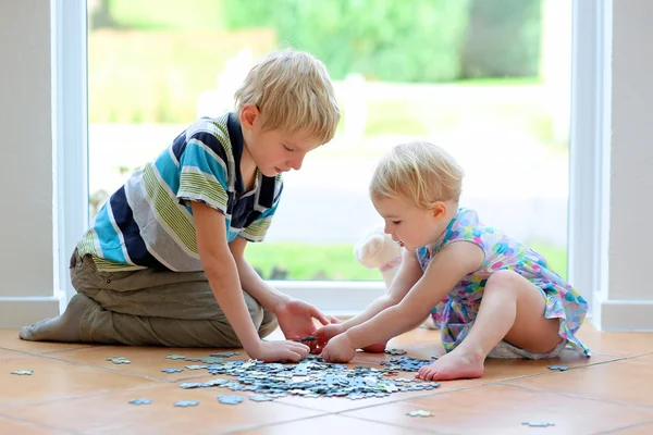 Ragazza che gioca puzzle con il suo fratello adolescente — Foto Stock