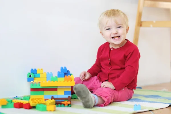 Baby girl playing with colorful plastic building blocks — Stock Photo, Image