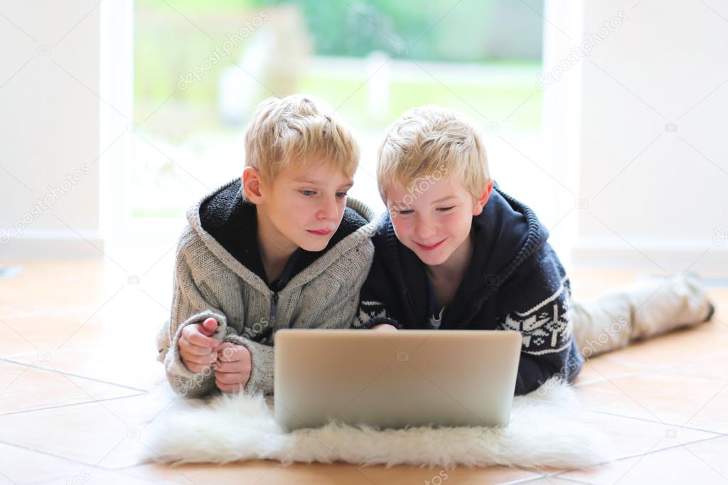 Brothers with notebook laying indoor
