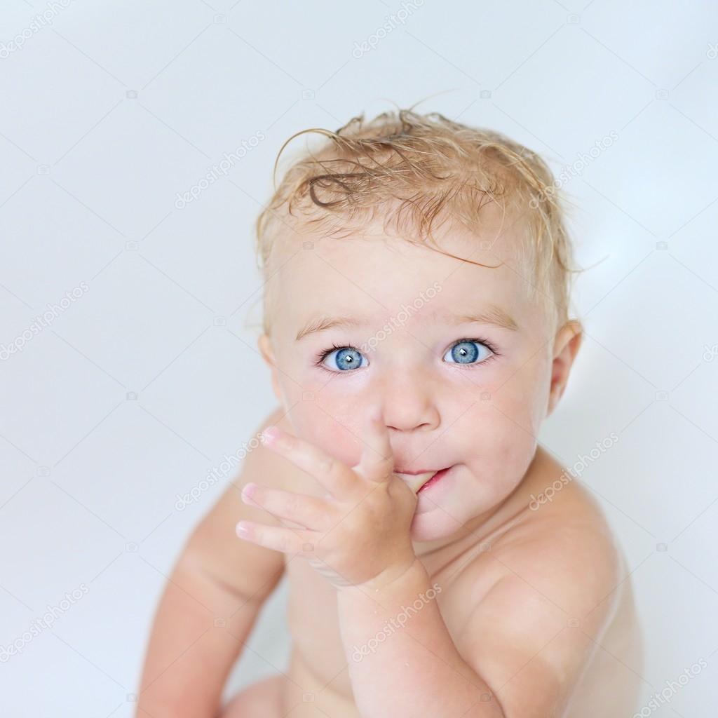 Baby girl in a bath sucking on her thumb