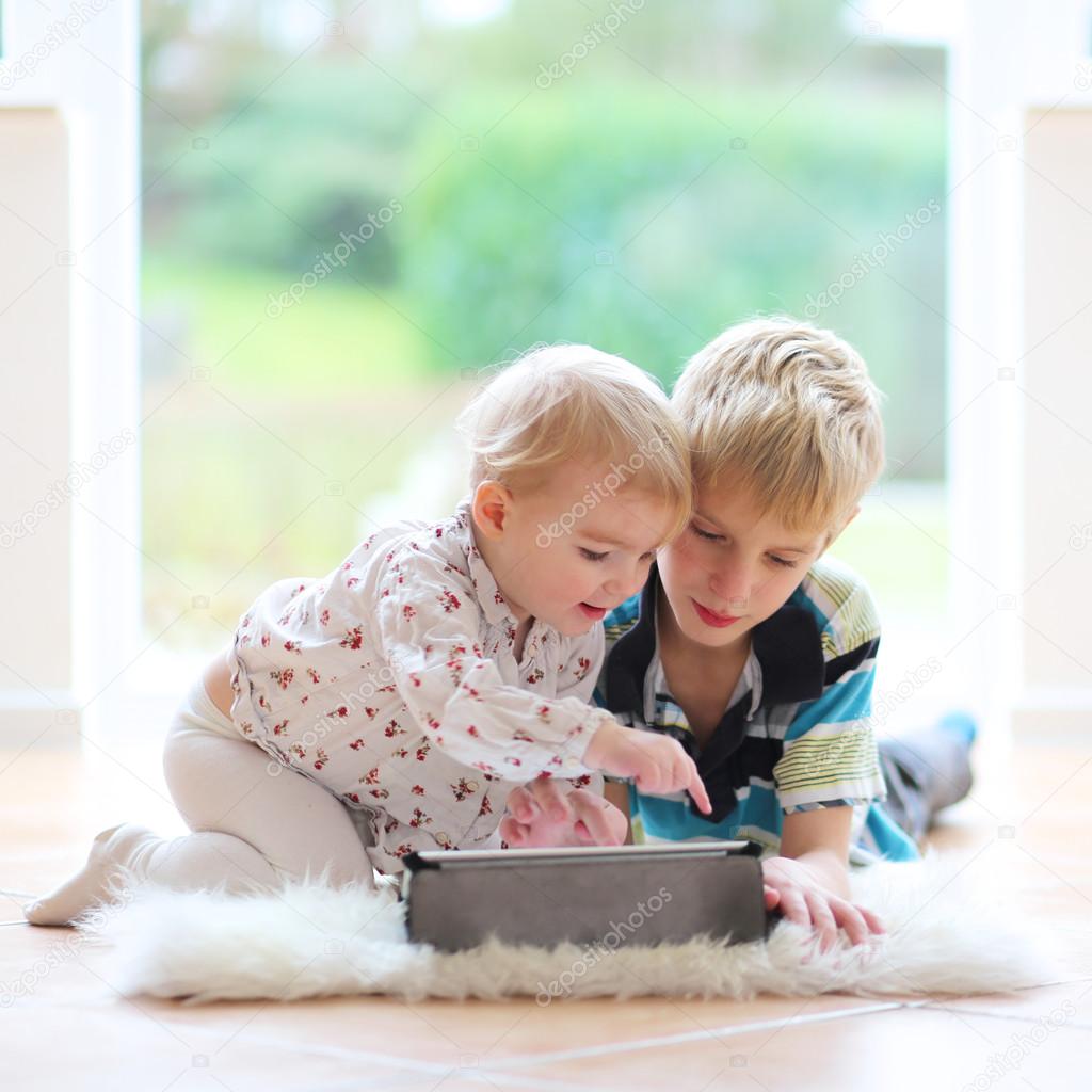 Boy with toddler sister playing on tablet pc